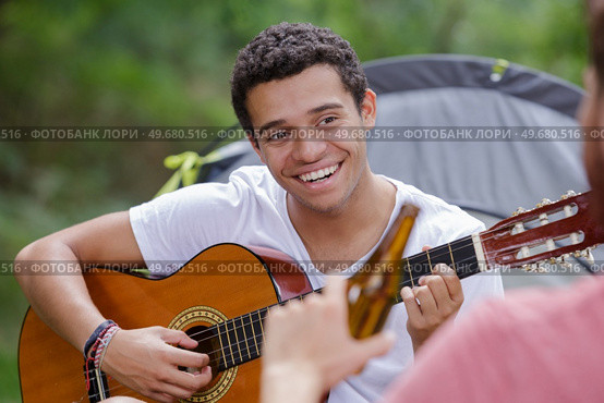 happy man playing guitar outside tent. Стоковое фото, агентство Ingram Publishing / Фотобанк Лори
