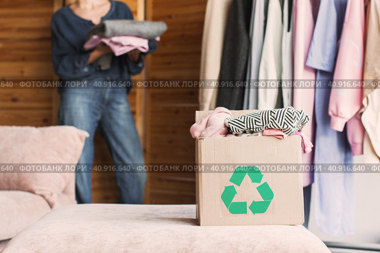 Happy middle aged woman holding cardboard recycling box with clothes. Стоковое фото, фотограф Гладских Татьяна / Фотобанк Лори