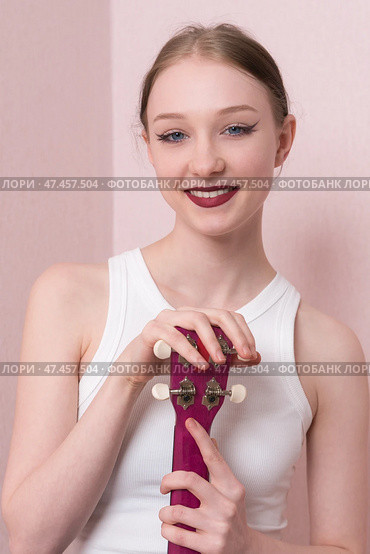 Happy woman musician holding ukulele, her face is full of joy and she's looking at camera with smile. Стоковое фото, фотограф А. А. Пирагис / Фотобанк Лори