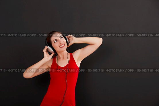 Happy woman over a black background listen music with headphones. Стоковое фото, агентство Ingram Publishing / Фотобанк Лори