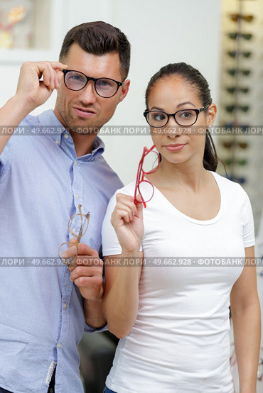 happy young couple choosing together eyeglasses in optical store. Стоковое фото, агентство Ingram Publishing / Фотобанк Лори