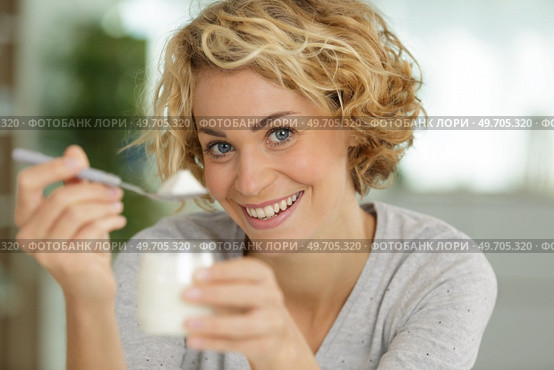happy young woman eating yogurt in kitchen. Стоковое фото, агентство Ingram Publishing / Фотобанк Лори