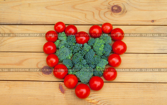 Heart healthy vegetables concept. Ripe red tomatoes in heart shape and green broccoli cabbage on wooden garden table. Organic farm products. Flat lay, close-up, top view, copy space. Стоковое фото, фотограф Виктория Катьянова / Фотобанк Лори