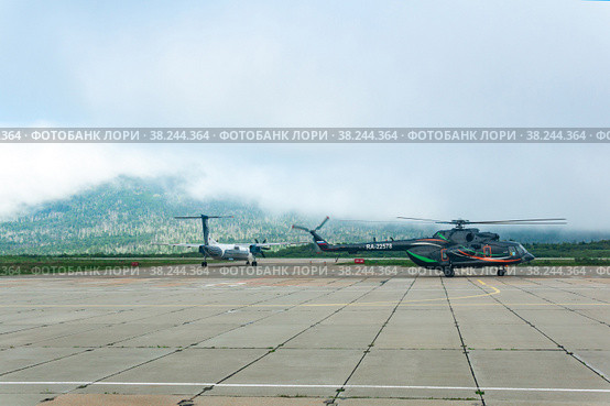 Helicopter and plane at the airport of Kunashir island preparing for takeoff (2022 год). Редакционное фото, фотограф Евгений Харитонов / Фотобанк Лори