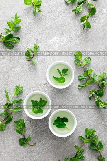 Herbal mint tea in small traditional chinese cups and fresh leaves, healthy antioxidant drink. Стоковое фото, агентство Ingram Publishing / Фотобанк Лори