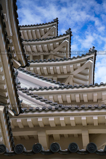 Himeji, Japan - Sep 24 2024, vertical, a view from bellow of the corners of multi-level roofs of Himeji Castle, the White Heron Castle, with a cloudy sky on background, without people, Himeji, Japan. Стоковое фото, фотограф Сергей Богомяко / Фотобанк Лори
