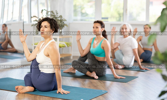 Hispanic woman performing seated twisting asana Matsyendrasana. Стоковое фото, фотограф Яков Филимонов / Фотобанк Лори