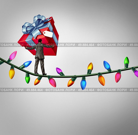 Holiday risk concept as a person holding a giant gift on a high wire tightrope made from christmas lights as a debt and credit metaphor and symbol of the challenges of giving. Стоковое фото, агентство Ingram Publishing / Фотобанк Лори