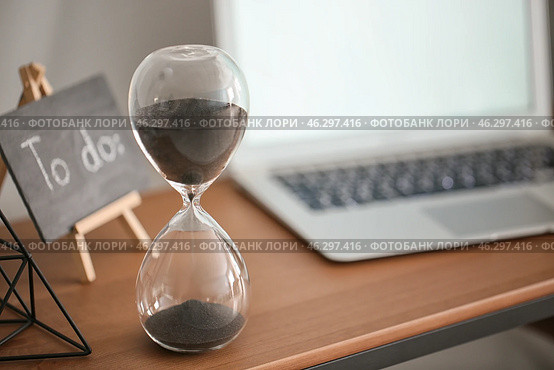 Hourglass with laptop on table in office. Time management concept. Стоковое фото, фотограф Pixel_shot / Фотобанк Лори