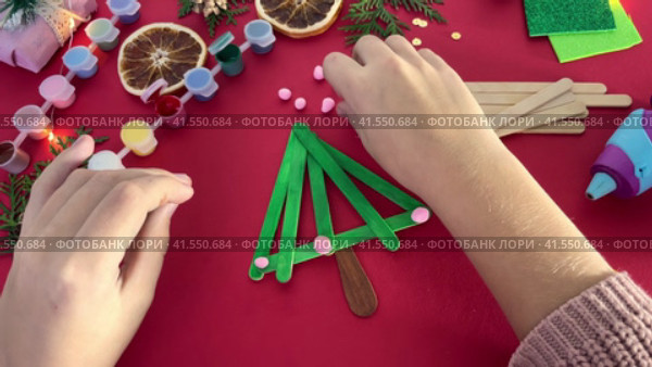 How to make christmas tree from ice cream sticks. Child decorates with pink balls New year handmade craft tree. Concept of DIY and kid's creativity. Стоковое видео, видеограф Ирина Старикова / Фотобанк Лори