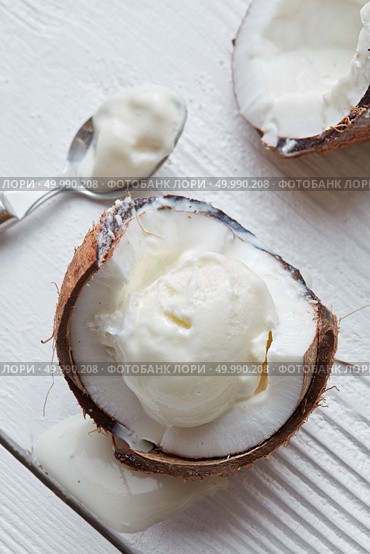 Ice cream in a half of coconut with a spoon On white wooden background. Delicious coconut ice cream. Стоковое фото, агентство Ingram Publishing / Фотобанк Лори
