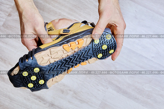 Ice grippers with yellow metal spikes and rubber base are securely fitted to hiking boot for stability on icy terrain. Стоковое фото, фотограф Владимир Григорьев / Фотобанк Лори
