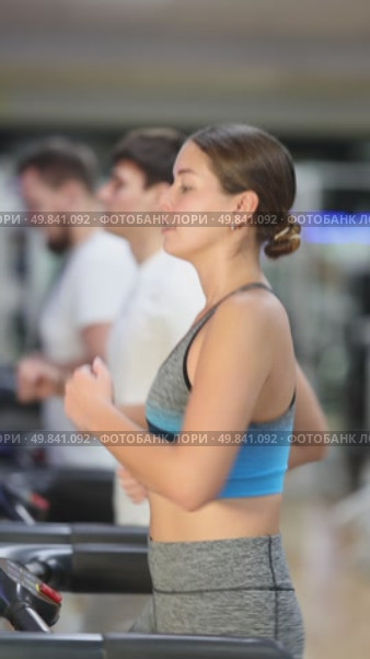 In gym, girl does exercises using treadmill. Young group of athletes trains in gym. Physical education and sports, active healthy lifestyle. Стоковое видео, видеограф Яков Филимонов / Фотобанк Лори