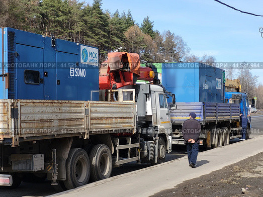 Industrial generators on cargo trucks with "SDMO" and "MSK energo" logos parked on roadside with workers. Equipment transport - Moscow, Russia, March 20, 2023. Редакционное фото, фотограф Андрей Журавлев / Фотобанк Лори