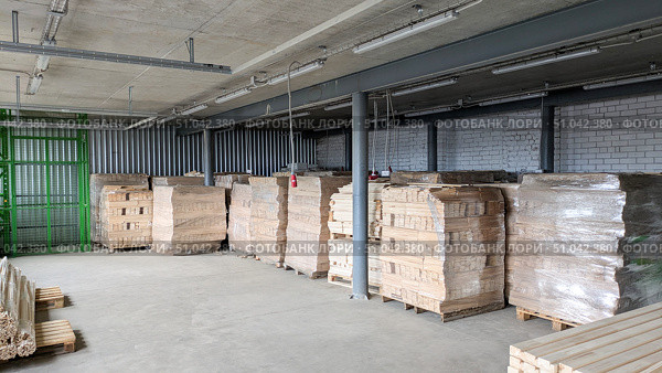 Industrial warehouse stores stacks of wood planks and pallets wrapped in plastic film, ready for storage and transportation. Стоковое фото, фотограф Елена Никишина / Фотобанк Лори