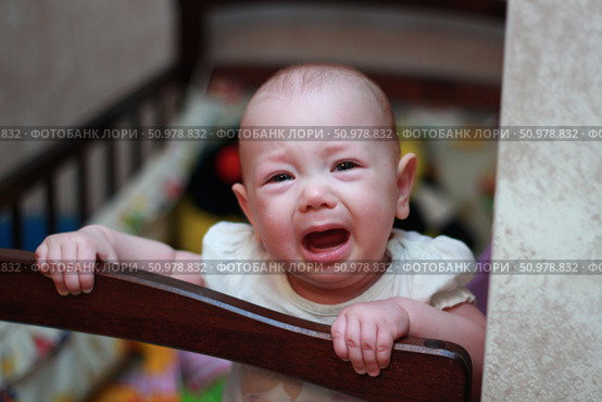 Infant Emotions: Crying Baby in Crib - Motherhood and Parenting in Early Childhood Development. Стоковое фото, фотограф Максимова Марина / Фотобанк Лори