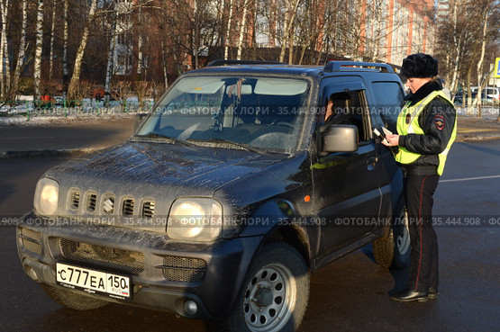 Инспектор дорожно-патрульной службы полиции проверяет документы водителя остановленного автомобиля (2016 год). Редакционное фото, фотограф Free Wind / Фотобанк Лори