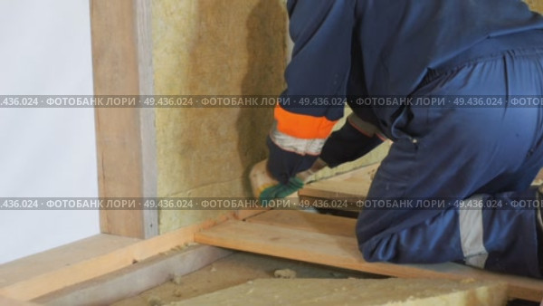 Insulation of a frame house with mineral wool. Cutting, fitting, laying insulation. Construction works. Стоковое видео, видеограф Константин Мерцалов / Фотобанк Лори