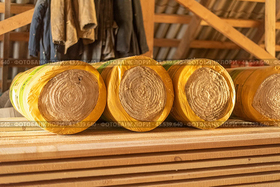Insulation rolls in yellow packaging in the attic of a wooden house. r. Стоковое фото, фотограф Дмитрий Львович Алферов / Фотобанк Лори