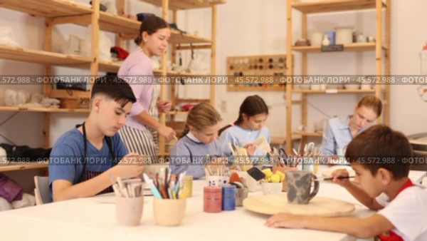 Interested children of different ages painting ceramic objects with teacher in art studio. Стоковое видео, видеограф Яков Филимонов / Фотобанк Лори