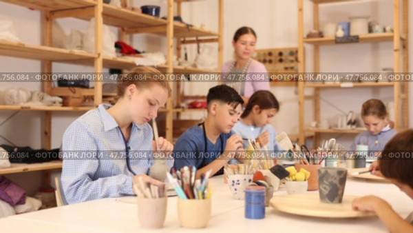 Interested children of different ages painting ceramic objects with teacher in art studio. Стоковое видео, видеограф Яков Филимонов / Фотобанк Лори