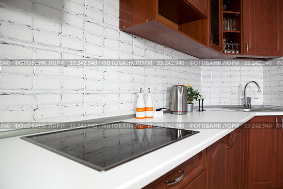 Interior of domestic kitchen with cooktop electric touch stove and long white tabletop with sink. Стоковое фото, фотограф Кекяляйнен Андрей / Фотобанк Лори