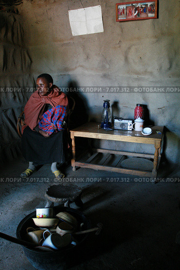 Internal view Masai home, black girl with baby are indoors. Внутреннее убранство жилища масаев,  чернокожая женщина в интерьере хижины, посуда и личные вещи, деревня масаев недалеко от змеиного парка, Аруша, Танзания. (2008 год). Редакционное фото, фотограф Владимир Григорьев / Фотобанк Лори