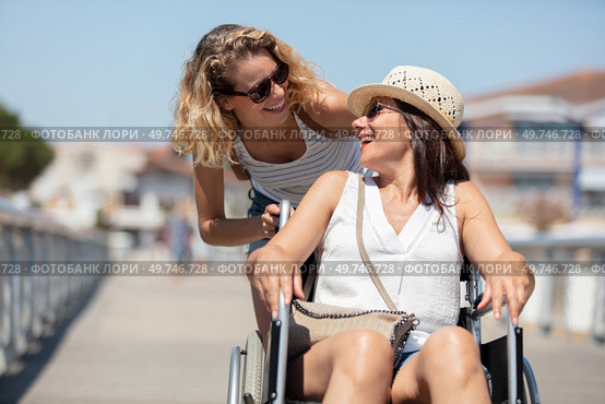 invalid girl on the wheelchair with friend outdoors. Стоковое фото, агентство Ingram Publishing / Фотобанк Лори