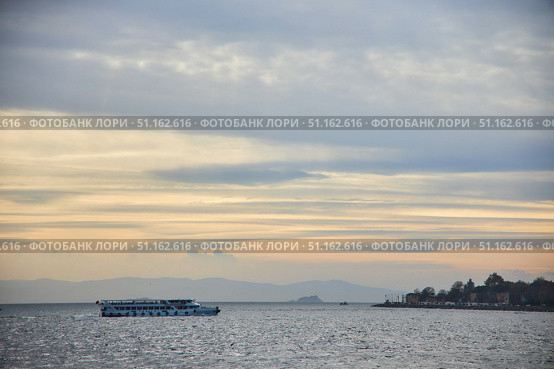 ISTANBUL, TURKEY - NOVEMBER 23, 2021: The Bosphorus Strait. Pleasure boat at sunset. Редакционное фото, фотограф Наталия Кирсанова / Фотобанк Лори