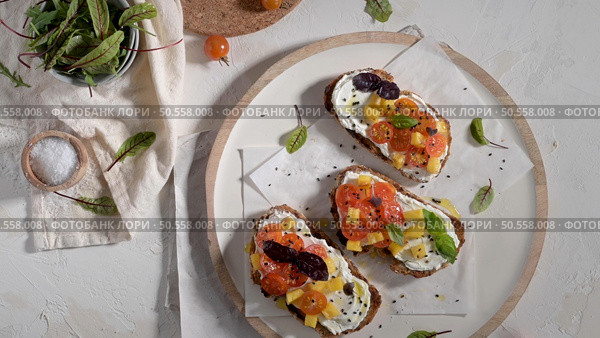 Italian bruschettas with roasted tomatoes, mozzarella cheese, pineapple slices and herbs on a rustic kitchen countertop. Стоковое фото, агентство Ingram Publishing / Фотобанк Лори