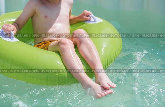 It's a hot day. A cute boy in sunglasses and a panama hat swims on a circle in a foam pool. The concept of summer holidays with children. Стоковое фото, фотограф Photojuli / Фотобанк Лори