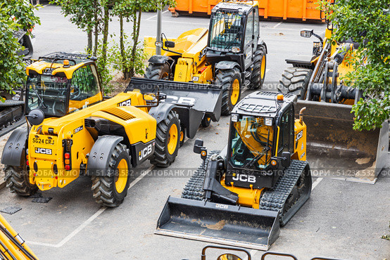 JCB telehandler, skid steer, and wheel loader parked in urban lot. London, UK, 14 July 2024. Редакционное фото, фотограф Zydrius Tartenis / Фотобанк Лори