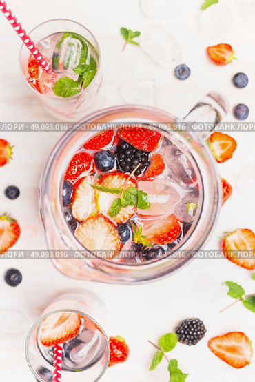 Jug with Infused detox water and berries on white wooden background, top view, close up. Стоковое фото, агентство Ingram Publishing / Фотобанк Лори