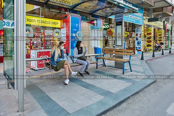 Just before curfew, young Turkish women wait for public transport while sitting on bus stop bench. (2021 год). Редакционное фото, фотограф Владимир Григорьев / Фотобанк Лори