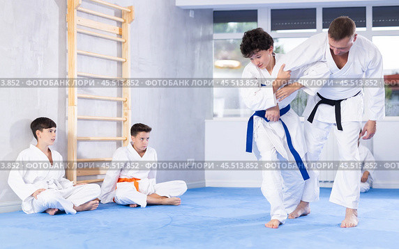 Karate sensei demonstrating fighting techniques to disciples during kumite with boy. Стоковое фото, фотограф Яков Филимонов / Фотобанк Лори