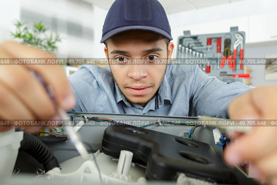 keen young serviceman repairing appliance. Стоковое фото, агентство Ingram Publishing / Фотобанк Лори