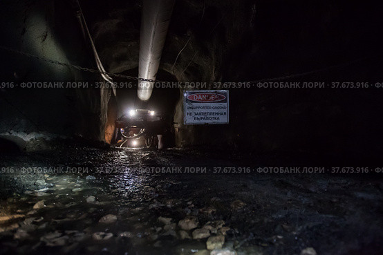 Khromtau, Aktobe region, Kazakhstan - May 06 2012: Gold mine underground gallery. Ore mining machine and warning sign "Unsupported ground" on chain. Стоковое фото, фотограф Alexey Rezvykh / Фотобанк Лори