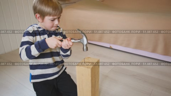 Kid hammers nails to wood with a hammer. Little boy helping with toy tools. Funny 6 years child having fun on building. Kid hammering crafting stuff using wooden pieces. Carpentry and family concept. Стоковое видео, видеограф Марина Демидюк / Фотобанк Лори