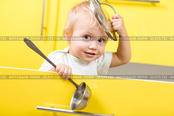 Kid sitting inside yellow opened kitchen box with laddle. Стоковое фото, фотограф Оксана Кузьмина / Фотобанк Лори