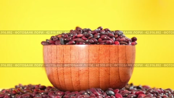 Kidney beans falling in wooden bowl on yellow background, slow motion. Dry red bean texture. Copy space. Lots of Beans rotating on turntable Close up. Diet, vegetarianism. Healthy Food. Legume grains. Стоковое видео, видеограф Марина Демидюк / Фотобанк Лори