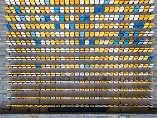 KIEV, UKRAINE - July 19, 2018. National Sports Complex Olimpiysky, aerial view from drone to a tribune with blue and yellow colors in a summer time before match.. KYIV, UKRAINE - July 19, 2018. Top view of empty tribunes of NSC Olimpiysky in blue and yellow colors before the game. Редакционное фото, агентство Ingram Publishing / Фотобанк Лори