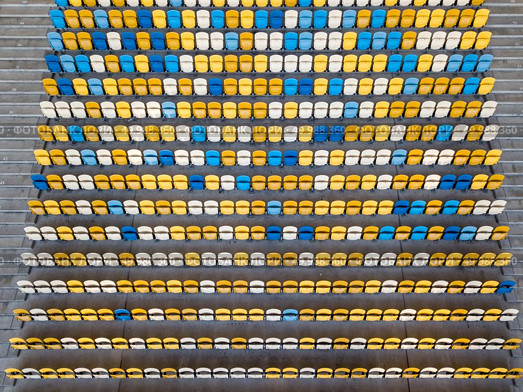 KIEV, UKRAINE - July 19, 2018. National Sports Complex Olimpiysky, aerial view from drone to a tribune with blue and yellow colors in a summer time before match.. KIEV, UKRAINE - July 19, 2018.Panoramic view from drone of tribunes with yellow and blue seats of National Sports Complex Olimpiysky on a summer day at sunset. Редакционное фото, агентство Ingram Publishing / Фотобанк Лори