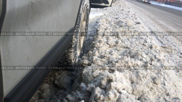 Колесо автомобиля медленно проезжает по снеговой каше городской улицы. Стоковое видео, видеограф Кекяляйнен Андрей / Фотобанк Лори