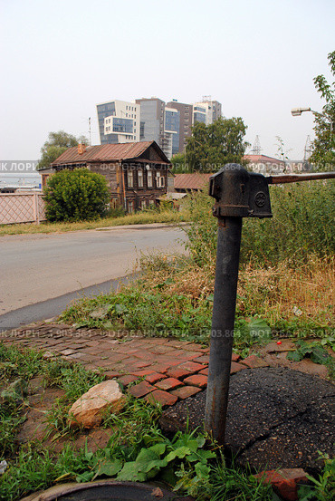 Колонка и старый дом на фоне современного строения (2010 год). Стоковое фото, фотограф Надежда Коновалова / Фотобанк Лори