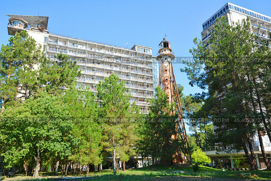 Корпуса "Маяк" и "Амзара" Объединения пансионатов "Курорт Пицунда". Между ними - достопримечательность "Старинный маяк". Республика Абхазия, Гагрский район, Пицунда (2021 год). Редакционное фото, фотограф Александр Замараев / Фотобанк Лори