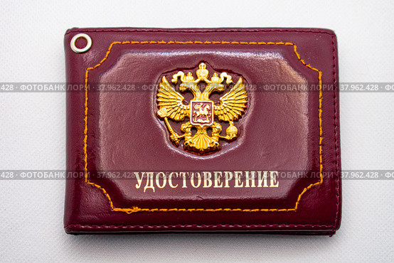 Красная обложка удостоверения с двуглавым орлом - гербом России крупным планом на белом фоне (2022 год). Редакционное фото, фотограф Анна Аникова / Фотобанк Лори