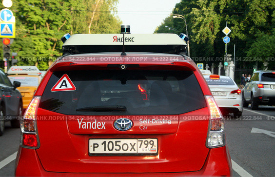 Красный беспилотный автомобиль Яндекса на улице (Yandex Self-Driving Car). Знак «А» на заднем стекле ("Автопилот").  Москва, Ломоносовский проспект (2020 год). Редакционное фото, фотограф Щеголева Ольга / Фотобанк Лори