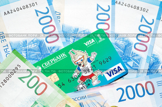 Кредитная карта Visa с Забивакой - талисманом Чемпионата мира по футболу FIFA лежит на новых денежных купюрах (2018 год). Редакционное фото, фотограф Елена Коромыслова / Фотобанк Лори