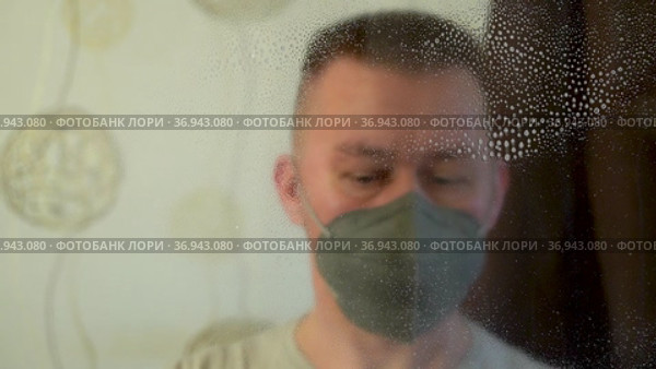 Крупно портрет мужчины в респираторной маске и перчатках дезинфицирует поверхность окна спреем и тряпкой. Стоковое видео, видеограф Sergei Gorin / Фотобанк Лори