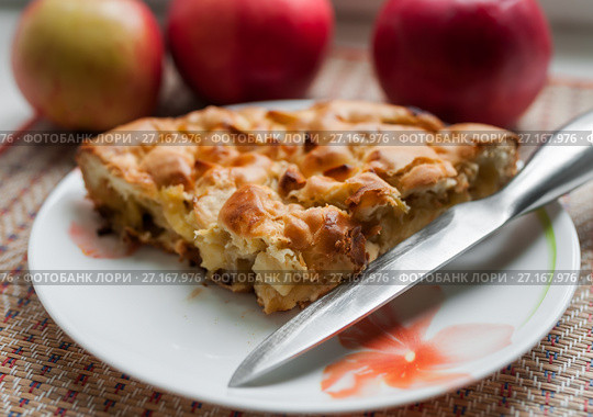 Кусочек шарлотки с яблоками и ножик на фоне красных яблок. Стоковое фото, фотограф Игорь Низов / Фотобанк Лори